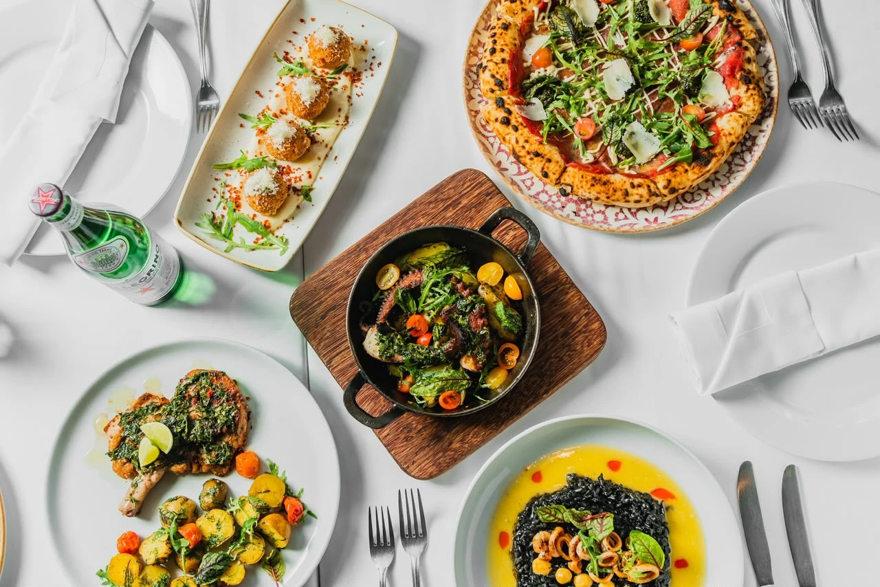 Mesa italiana con pizza, arancini y risotto nero