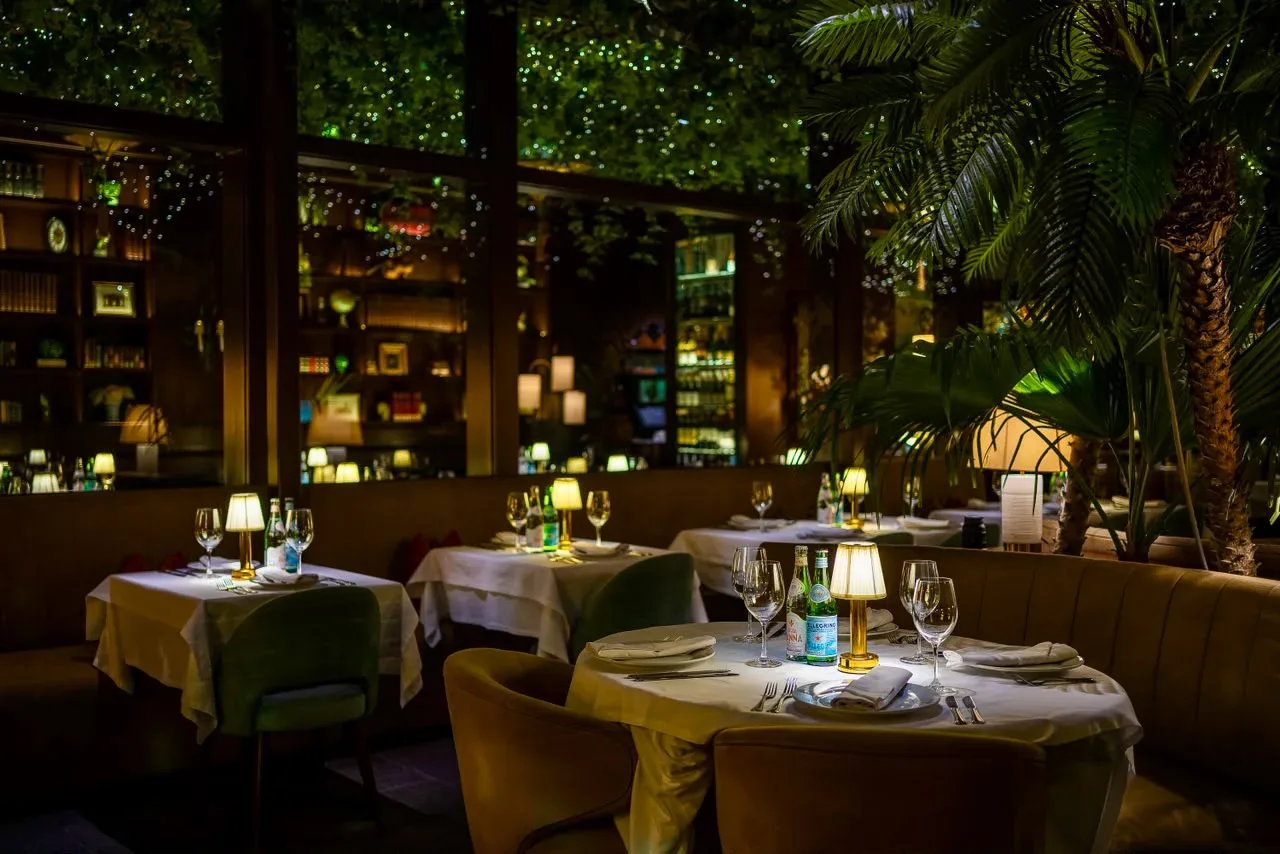 Salón de noche con lámparas y palmeras